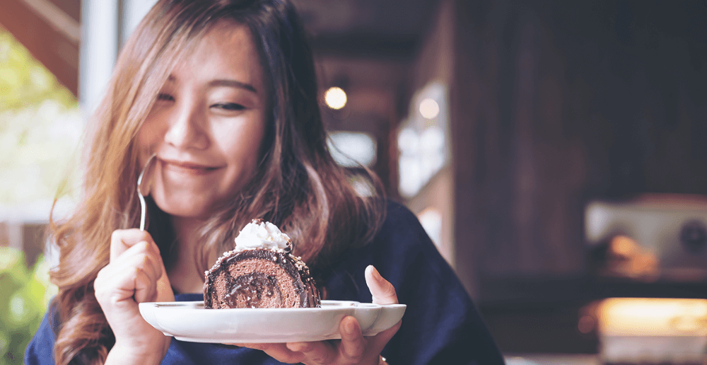 Photo of a woman eating a dessert.