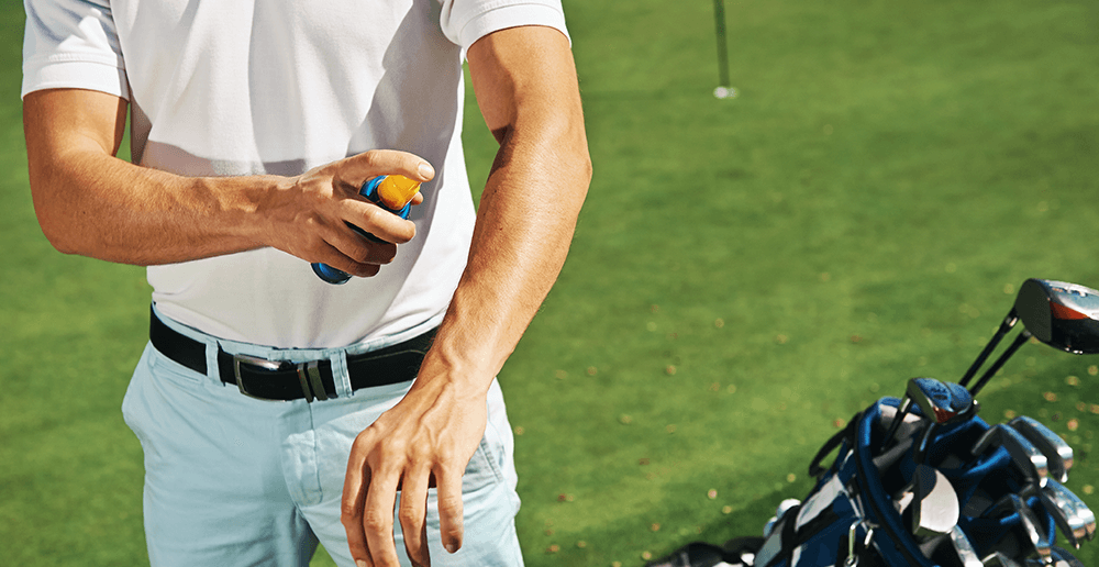 Photo of a golfer putting on sunscreen